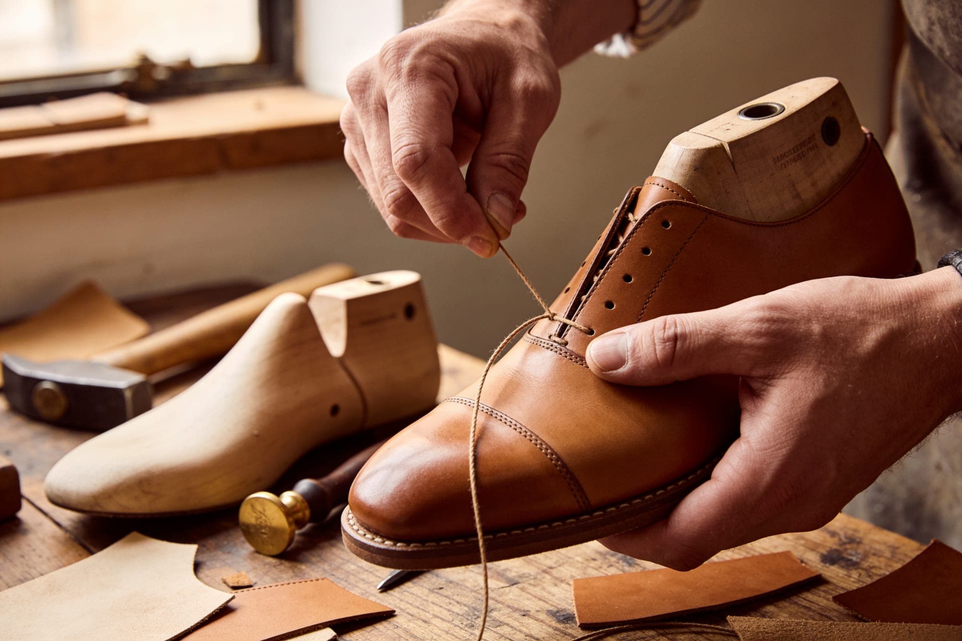 Mani di un artigiano che cuciono il guardolo di una scarpa