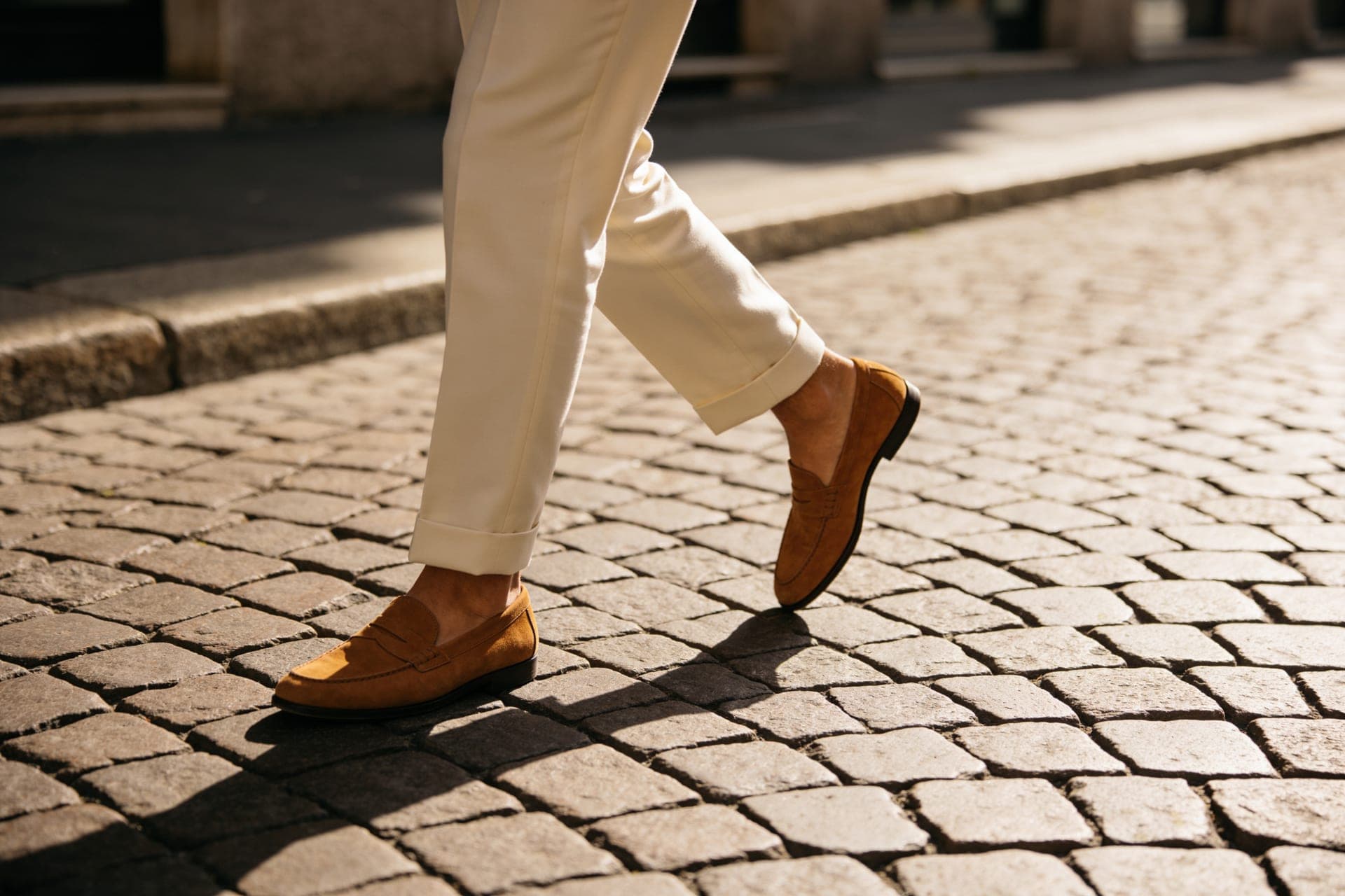 Persona in pantaloni color crema e mocassini in pelle su una strada di Milano